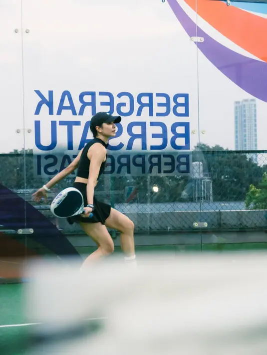 Topi hitam Nike yang senada melindungi wajahnya dari sorotan cahaya sambil melengkapi gaya atletisnya. [@miktambayong].