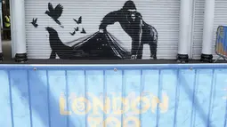 Sebuah mural karya seniman jalanan yang sulit dipahami, Banksy, menunjukkan seekor gorila yang memegang gerbang masuk sementara burung-burung terbang dan seekor singa laut melenggang pergi.  (Stefan Rousseau/PA via AP)