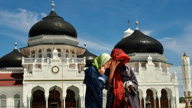 Turis asing mengenakan jilbab saat mengunjungi Masjid Agung Baiturrahman di Banda Aceh, Aceh pada 6 Agustus 2019. Selain sebagai tempat ibadah, Masjid Baiturahman juga menjadi tempat wisata bagi turis lokal dan mancanegara. (CHAIDEER MAHYUDDIN / AFP)