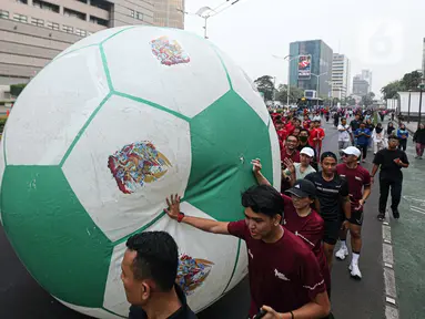 Masyarakat mengglindingkan bola raksasa dari Sarina ke Bundaran HI saat Trophy Experience Piala Dunia U-17 2023 di car free day (CFD) kawasan Jalan Thamrin, Jakarta, Minggu (15/10/2023). Kegiatan tersebut dalam rangka promosi ajang Piala Dunia U-17 2023 di Indonesia. (Liputan6.com/Faizal Fanani)