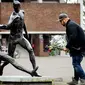 Seorang pria akan meletakan bunga di depan patung Johan Cruyff yang terdapat di sekitar Stadion Amsterdam Arena, Amsterdam, Kamis (24/3/2016). Mantan bintang timnas Belanda itu meninggal pada usia 68 tahun. (AFP/Koen Van Weel)