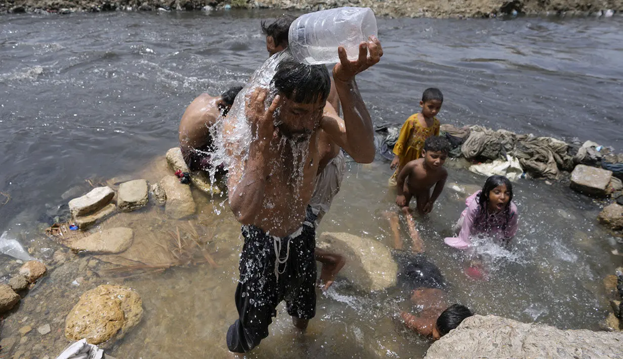 <p>Orang-orang mendinginkan diri di sungai saat suhu mencapai 35 C (95 F) di Karachi, Pakistan, 13 Juli 2023. (AP Photo/Fareed Khan)</p>