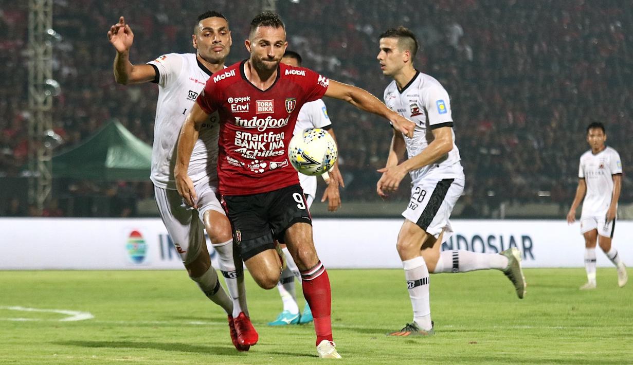 Striker Bali United, Ilija Spasojevic, berebut bola dengan bek Madura United, Jaimerson Xavier, pada laga Liga 1 2019 di Stadion Kapten I Wayan Dipta, Bali, Minggu (22/12). Bali kalah 0-2 dari Madura. (Bola.com/Aditya Wany)