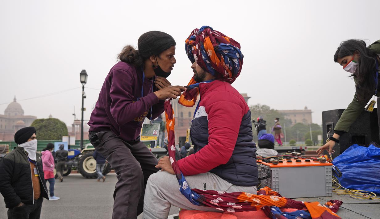 Seorang pria mengikat sorban seorang seniman saat mereka berlatih untuk parade Hari Republik mendatang, di New Delhi, India (17/1/2022). Parade akan ditandai dengan pawai oleh berbagai cabang militer serta tampilan senjata dan rudal. (AP Photo/Manish Swarup)