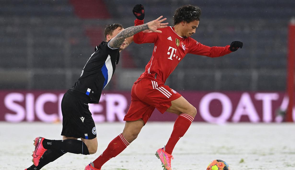 Gelandang Bayern Munich, Leroy Sane (kanan) menggiring bola dibayangi bek Arminia Bielefeld, Jacob Barrett Laursen dalam laga lanjutan Liga Jerman 2020/21 pekan ke-21 di Allianz Arena, Munich, Senin (15/2/2021). Bayern Munich bermain imbang 3-3 dengan Arminia Bielefeld. (AFP/Christof Stache/Pool)