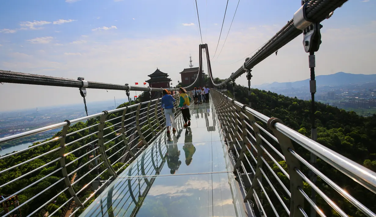 Foto yang diambil pada 4 Mei 2019 menunjukkan orang-orang berjalan di atas jembatan berlantai kaca di Huaxi Adventure Park, Provinsi Jiangsu timur China. Jembatan kaca setinggi 518 meter ini menjadi tujuan wisata favorit di China. (Photo by STR / AFP)