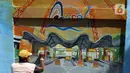Pekerja menyelesaikan pembuatan mural Kota Jakarta di Tanah Kusir, Kebayoran Lama, Jakarta, Jumat (26/11/2021). Mural tersebut bertemakan Kota Jakarta dengan gambar ikon seperti ondel-ondel, Monas hingga transportasi. (Liputan6.com/Herman Zakharia)