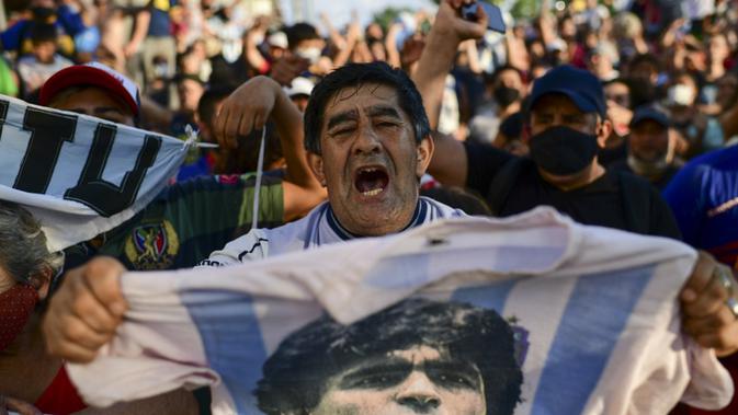 Fans berkumpul di luar kamar jenazah tempat jasad mendiang legenda sepak bola Argentina Diego Maradona akan menjalani otopsi di San Fernando, Buenos Aires, Argentina, 25 November 2020. Jenazah Diego Maradona akan disemayamkan di Istana Presiden. (RONALDO SCHEMIDT/AFP)