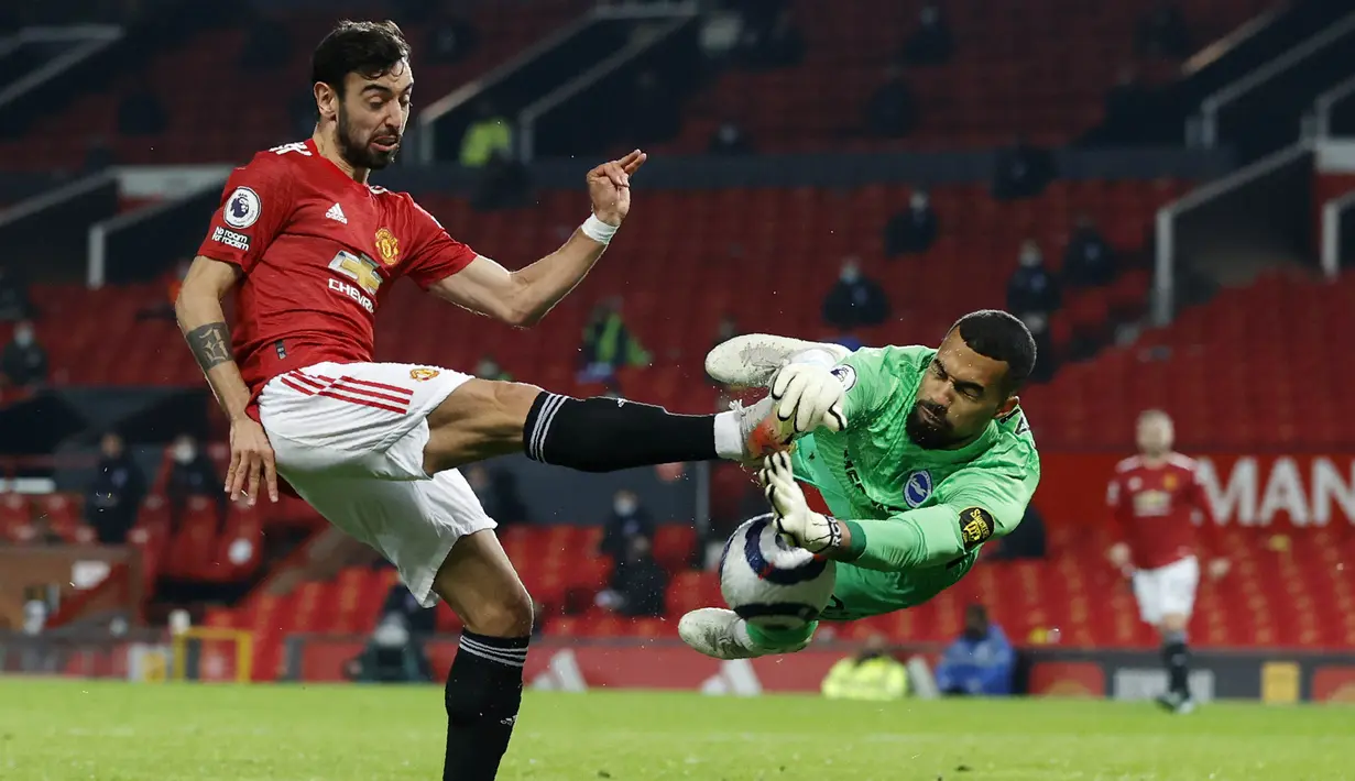 Penyerang Manchester United, Bruno Fernandes, berebut bola dengan kiper Brighton and Hove Albion, Robert Sanchez, pada laga Liga Inggris di Stadion Old Trafford, Minggu (4/4/2021). MU menang dengan skor 2-1. (Phil Noble/Pool via AP)