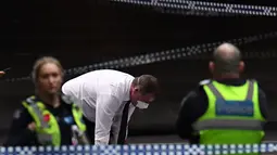 Polisi memeriksa jasad di TKP setelah insiden penikaman di Melbourne, Australia, Jumat (9/11). Akibat penyerangan ini satu orang tewas dan dua lainnya luka-luka. (William WEST/AFP)