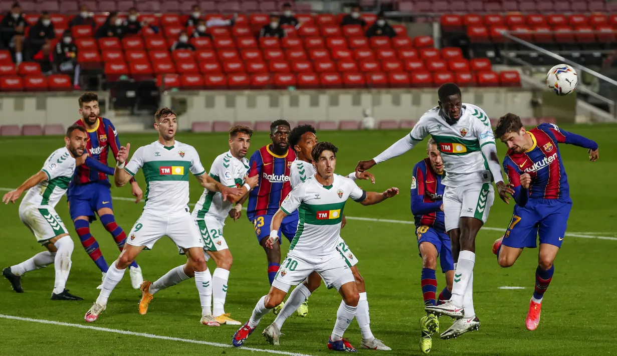 Penyerang Barcelona, Francisco Trincao dan gelendang Elche, Omenuke Mfulum melompat saat berebut bola pada lanjutan Liga Spanyol di Camp Nou, Kamis (25/2/2021) dini hari WIB. Barcelona menang 3-0 melalui dua gol yang  dicetak Lionel Messi dan satu gol lagi dicetak Jordi Alba. (AP Photo/Joan Monfort)