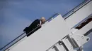 Presiden AS Joe Biden saat menaiki Air Force One di Pangkalan Udara Andrews, Maryland, Jumat (19/3/2021). Biden yang tersandung kemudian berdiri, berhenti sejenak dan mengusap kaki kirinya sebelum dia sampai di puncak tangga. (Eric BARADAT/AFP)