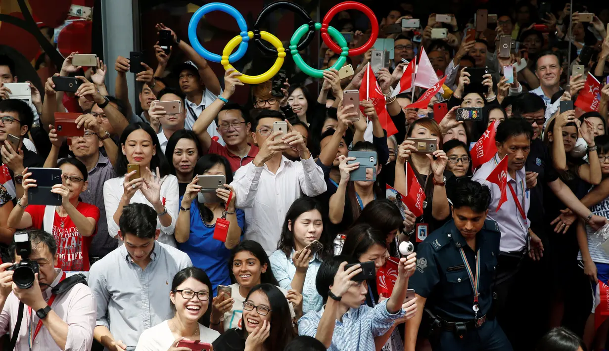 Ribuan warga Singapura mengabadikan momen kedatangan atlet renang peraih medali emas Olimpiade Rio Brasil Joseph Schooling saat parade kemenangan di Singapura (18/08). (REUTERS/Edgar Su)