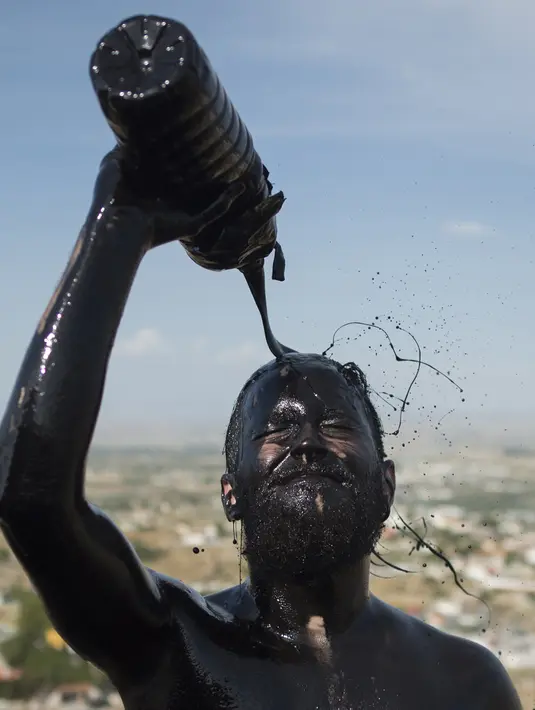 Seorang peserta menyiramkan minyak hitam ke tubuhnya saat mengikuti Festival Tradisionlal Cascamorras di Baza, Granada, Spanyol (6/9/2019). Festival Cascamorras menggambarkan kekuatan dan kemampuan Baza untuk mempertahankan Virgen de la Piedad. (AFP Photo/Jorge Guerrero)