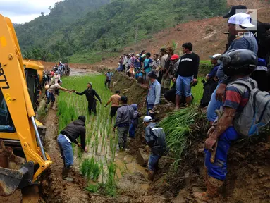 Warga memandu alat berat melalui jalan kecil menuju lokasi longsor di Dusun Cimapag, Sirnaresmi, Cisolok, Sukabumi, Jawa Barat, Selasa (1/1). Alat berat dikerahkan untuk mencari korban yang hilang. (Merdeka.com/Arie Basuki)