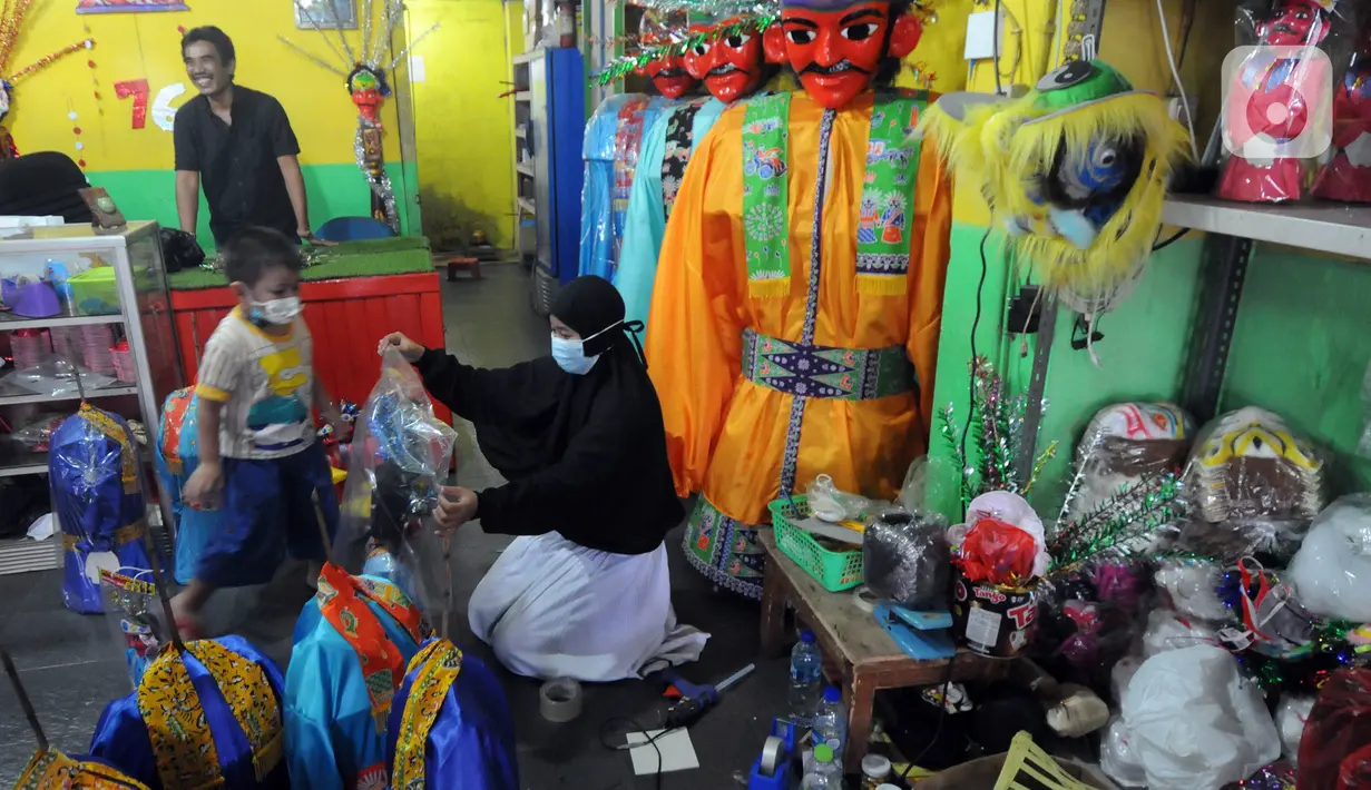 Seorang wanita memeriksa ondel-ondel di Rumah Produksi Ondel-Ondel Jakarta, Setu Babakan, Jakarta Selatan, Minggu (19/9/2021). Setelah stagnan dua tahun akibat pandemi COVID-19, produksi dan penjualan ondel-ondel pasca PPKM Level 3 mengalami kenaikan hingga 20 persen. (merdeka.com/Arie Basuki)