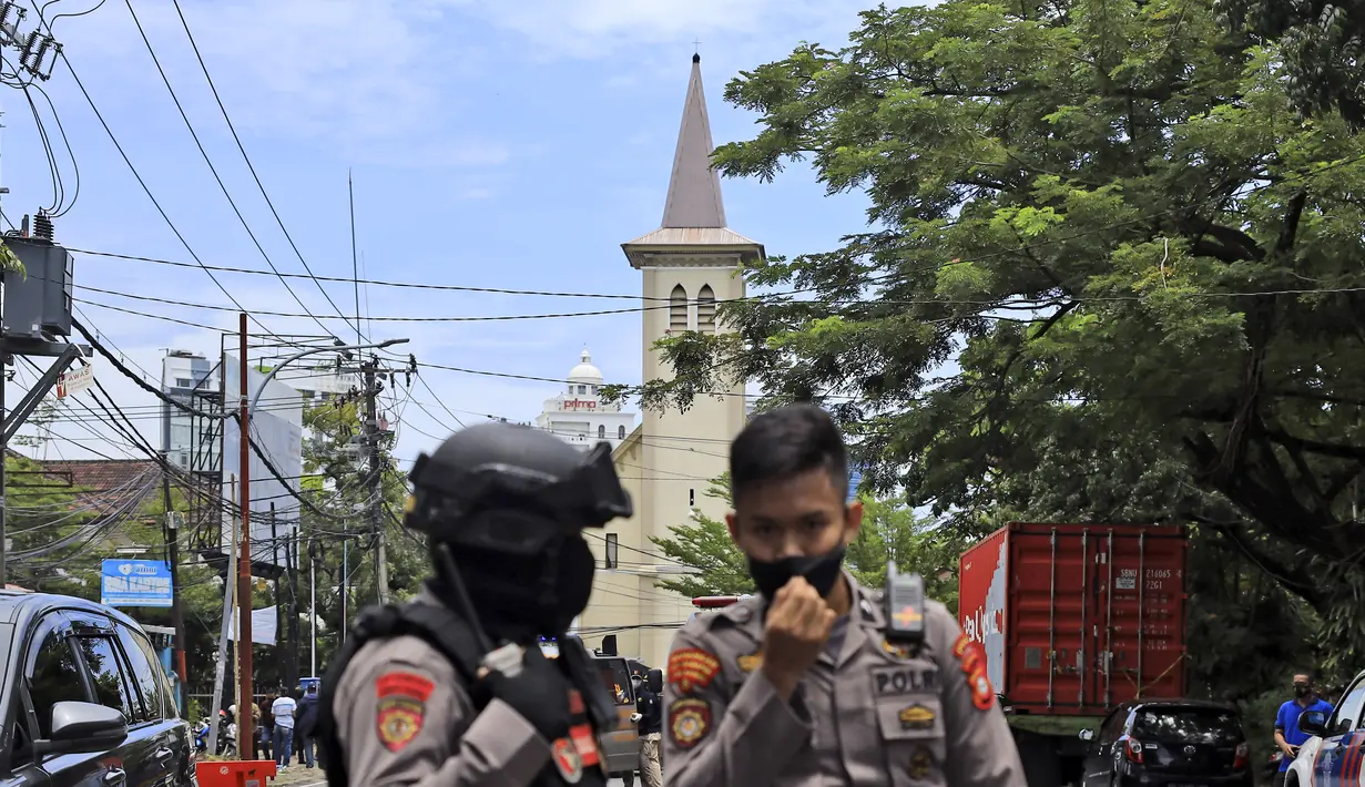 Petugas polisi berjaga di dekat sebuah gereja tempat ledakan meledak di Makassar, Sulawesi Selatan, Minggu (28/3/2021). Saat ini, akses di kawasan Katedral Makssar dibatasi. Pihak kepolisian masih berjaga-jaga di lokasi. (AP Photo/Yusuf Wahil)