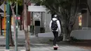 Seorang pria mengendarai skateboard listrik di sepanjang jalan setapak yang sepi di Perth (29/6/2021). Warga di Kota Perth, ibu kota Australia Barat, dan wilayah tetangga Peel harus tinggal di rumah kecuali untuk alasan mendesak. (AFP/Trevor Collens)