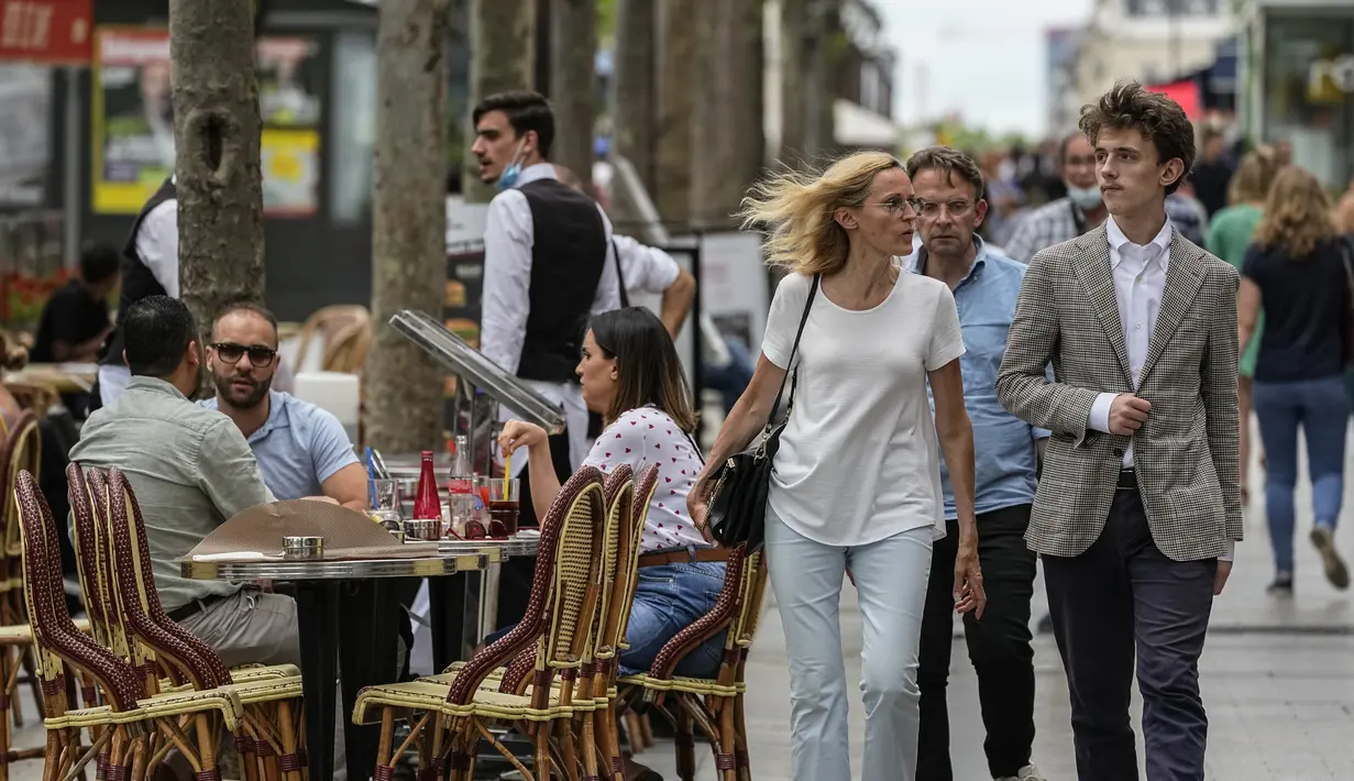 Orang-orang melintasi jalan Champs Elysees di Paris, Kamis (17/6/2021). Prancis mengumumkan melonggarkan aturan pembatasan COVID-19, mencabut aturan penggunaan masker di luar ruangan dan menghentikan jam malam mulai pekan ini setelah delapan bulan terakhir. (AP Photo/Michel Euler)