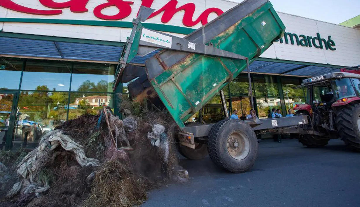 Petani menumpahkan truk penuh sampah dan kotoran di depan supermarket Casino di Sarlat, Perancis barat daya, sebagai bentuk demo di supermarket tersebut, Kamis (20/8/2015). (AFP PHOTO/Yohan Bonnet)