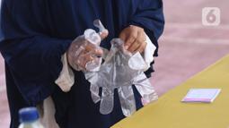 Pemiilih mengenakan sarung tangan plastik saat menggunakan hak suaranya dalam Pilkada Tangerang Selatan di TPS 23 Pondok Jagung Timur, Rabu (9/12/2020). Menggunakan masker hingga memakai sarung tangan plastik menjadi hal wajib saat melakukan pencoblosan di Pilkada 2020. (Liputan6.com/Angga Yuniar)