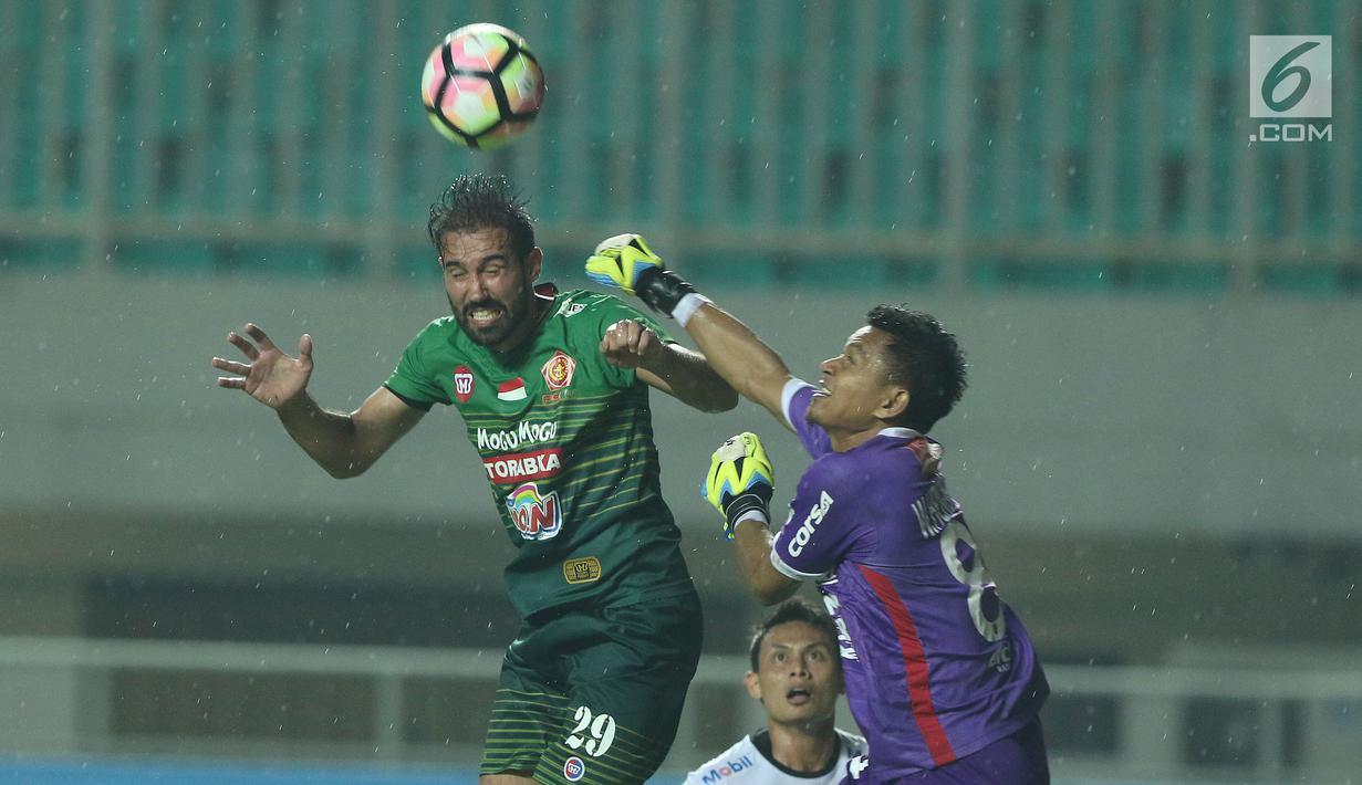 Pemain depan PS TNI, Elio Bruno Teixeira berebut bola dengan kiper Bali United, Wawan Hendrawan dilanjutan Liga 1 Indonesia di Stadion Pakansari, Kab Bogor, Senin (10/7). Bali United unggul 4-3. (Liputan6.com/Helmi Fithriansyah)