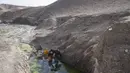 Dua bersaudara mengisi dirigen dengan air dari kolam tergenang sekitar 3 km dari rumah mereka di desa Kamar Kalagh di luar Herat, pada 26 November 2021. Kekeringan Afghanistan, yang terburuk dalam beberapa dekade, kini memasuki tahun kedua, diperburuk oleh perubahan iklim. (AP/Petros Giannakouris)