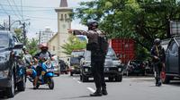 Seorang polisi  mengatur lalu lintas setelah ledakan di luar sebuah gereja di Makassar (28/3/2021). Pernyataan itu disampaikan setelah Tim Labfor melakukan olah Tempat Kejadian Perkara (TKP). Kepolisian menemukan jasad tepat di samping sepeda motor yang terjatuh. (AFP/Daeng Mansur)