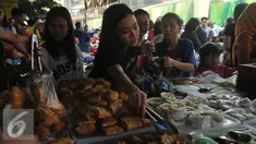 Pembeli mengambil sendiri kue yang dijajakan di Pasar Takjil Benhil, Jakarta, Senin (6/6). Harga yang relatif murah menjadikan pasar ini kerap ramai selama Ramadan. (Liputan6.com/Gempur M Surya)