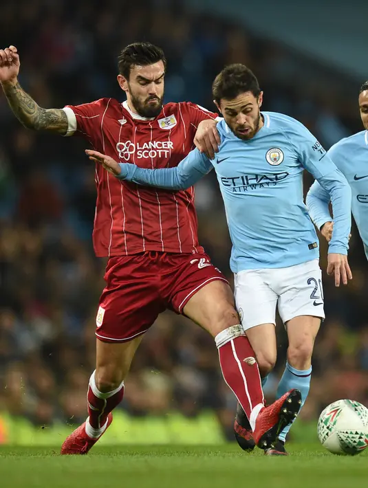 Pemain Manchester City, Bernardo Silva dan pemain Bristol City Marlon Pack berebut bola pada leg pertama semifinal Piala Liga Inggris di Stadion Etihad, Selasa (9/1). Man City menang 2-1 berkat gol telat Sergio Aguero di injury time. (Oli SCARFF / AFP)