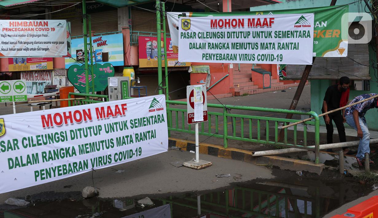 Warga melintasi palang bambu penutup pintu masuk kawasan Pasar Cileungsi, Kabupaten Bogor, Selasa (2/6/2020). Penutupan sementara kegiatan jual beli di Pasar Cileungsi terkait adanya tujuh pedagang yang positif terinfeksi virus COVID-19. (Liputan6.com/Helmi Fithriansyah)