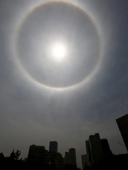 Pemandangan 'Halo Matahari' yang menghiasi langit Mexico City, Meksiko, Kamis (21/5). Menurut ahli meteorologi, fenomena optis berupa lingkaran cahaya atau pelangi di sekeliling matahari ini dibentuk oleh refleksi dari kristal es. (REUTERS/Edgard Garrido)
