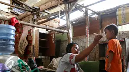 Seorang ibu saat memberikan makan kepada anaknya sambil menunggu jatah pembongkaran di kolong tol Pluit, Jakarta, Rabu (2/3). Pemprov DKI membongkar 385 bangunan berdasarkan Perda No 8 Tahun 2007 tentang ketertiban umum. (Liputan6.com/Yoppy Renato)