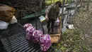 Seorang pedagang sayur Kashmir mencuci karung lobak sebelum membawanya ke pasar untuk dijual pada hari yang dingin di Srinagar, Kashmir yang dikuasai India, Minggu (26/12/2021). (AP Photo/Mukhtar Khan)