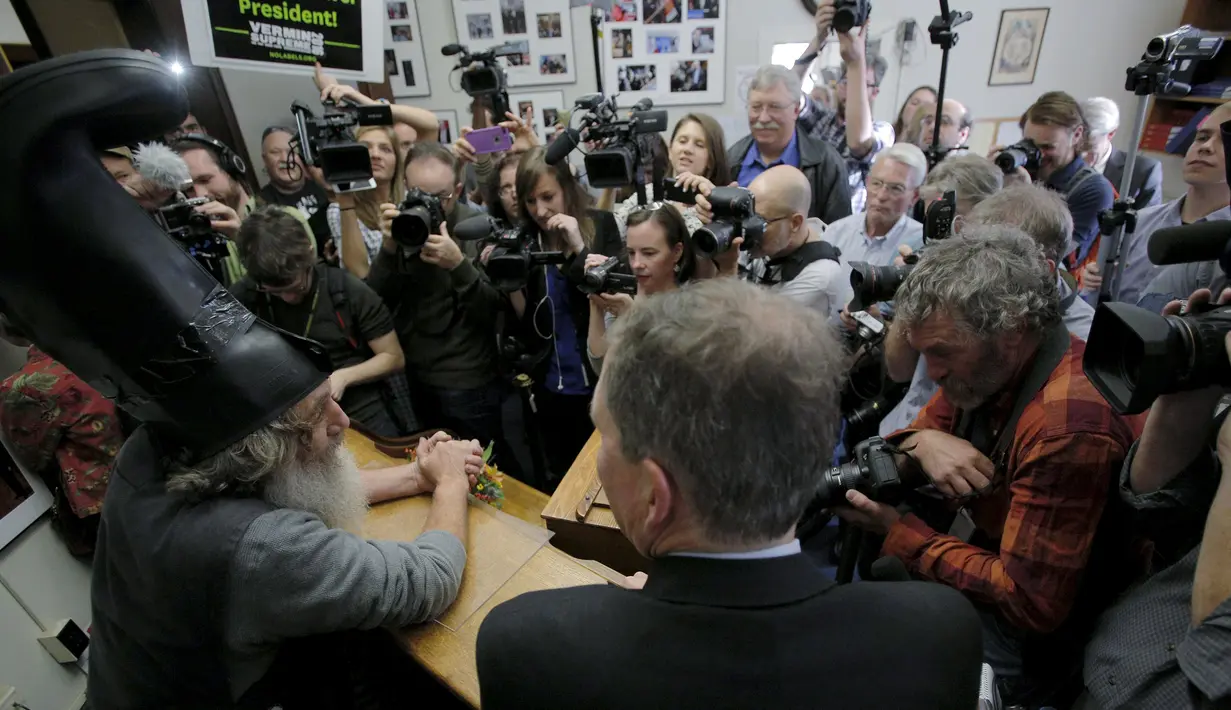 Awak media meliput Vermin Supreme saat mendeklarasikan diri sebagai kandidat calon presiden AS di New Hampshire, Jumat (20/11). Pria yang kerap tampil dengan topi sepatu bot ini sebelumnya pernah melakukan pencalonan pada 2012 lalu. (REUTERS/Brian Snyder)