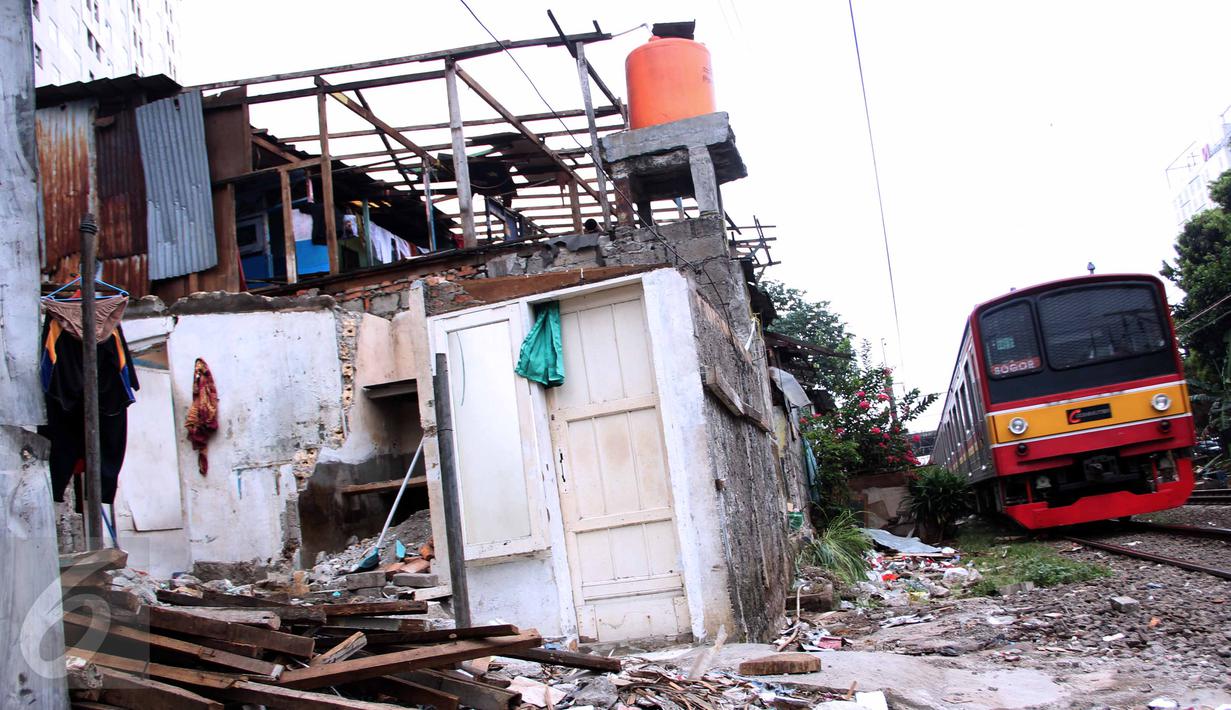 Sebuah KRL melintasi kawasan yang terkena pembongkaran di sekitar rel kereta api di kawasan Rawajati, Kalibata, Jakarta, Rabu (10/6/2015). Para warga rela membongkar sendiri rumahnya karena telah bermukim di lahan milik PT KAI. (Liputan6.com/Helmi Afandi)