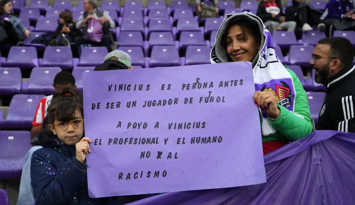Dua suporter muda menunjukkan spanduk bertuliskan dalam bahasa Spanyol, "Vinicius adalah seorang manusia sebelum menjadi pemain sepak bola. Saya mendukung Vinicius, seorang profesional dan manusia, tidak untuk rasisme" sebelum pertandingan La Liga Spanyol antara Valladolid vs Barcelona di stadion Jose Zorrilla Selasa, 23 Mei 2023. (AP Photo/Manu Fernandez)