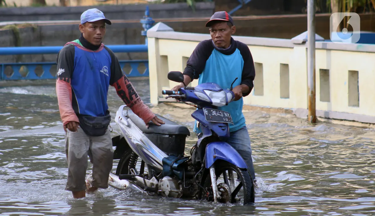 Warga mendorong motor saat melintasi genangan banjir rob yang menggenangi kawasan Pelabuhan Nizam Zachman, Muara Baru,  Jakarta, Jumat (5/6/2020). Banjir rob di Pelabuhan Muara Baru tersebut terjadi akibat cuaca ekstrem serta pasang air laut. (Liputan6.com/Helmi Fithriansyah)