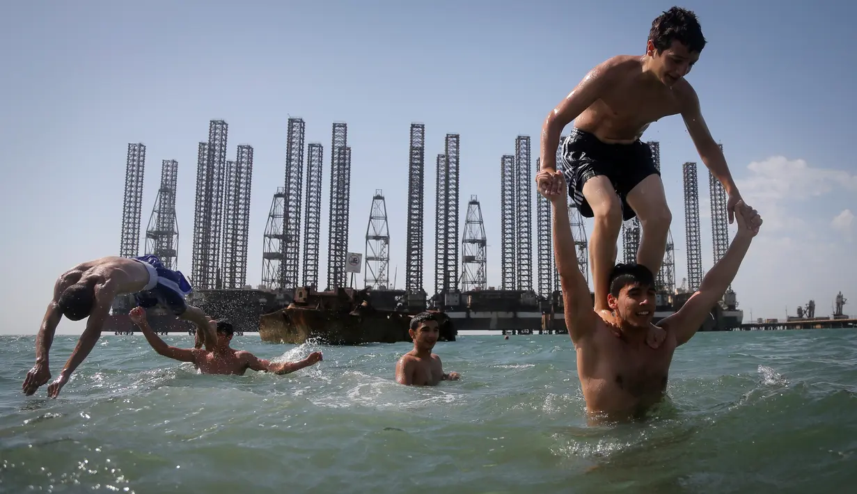 Anak-anak yang tergabung dalam sekolah kickboxing sedang berlatih di tepi Laut Kaspia dekat dengan bekas tempat pengeboran minyak era Soviet di kota Baku, Azerbaijan, Sabtu (27/6). (AP Photo/Dmitry Lovetsky)