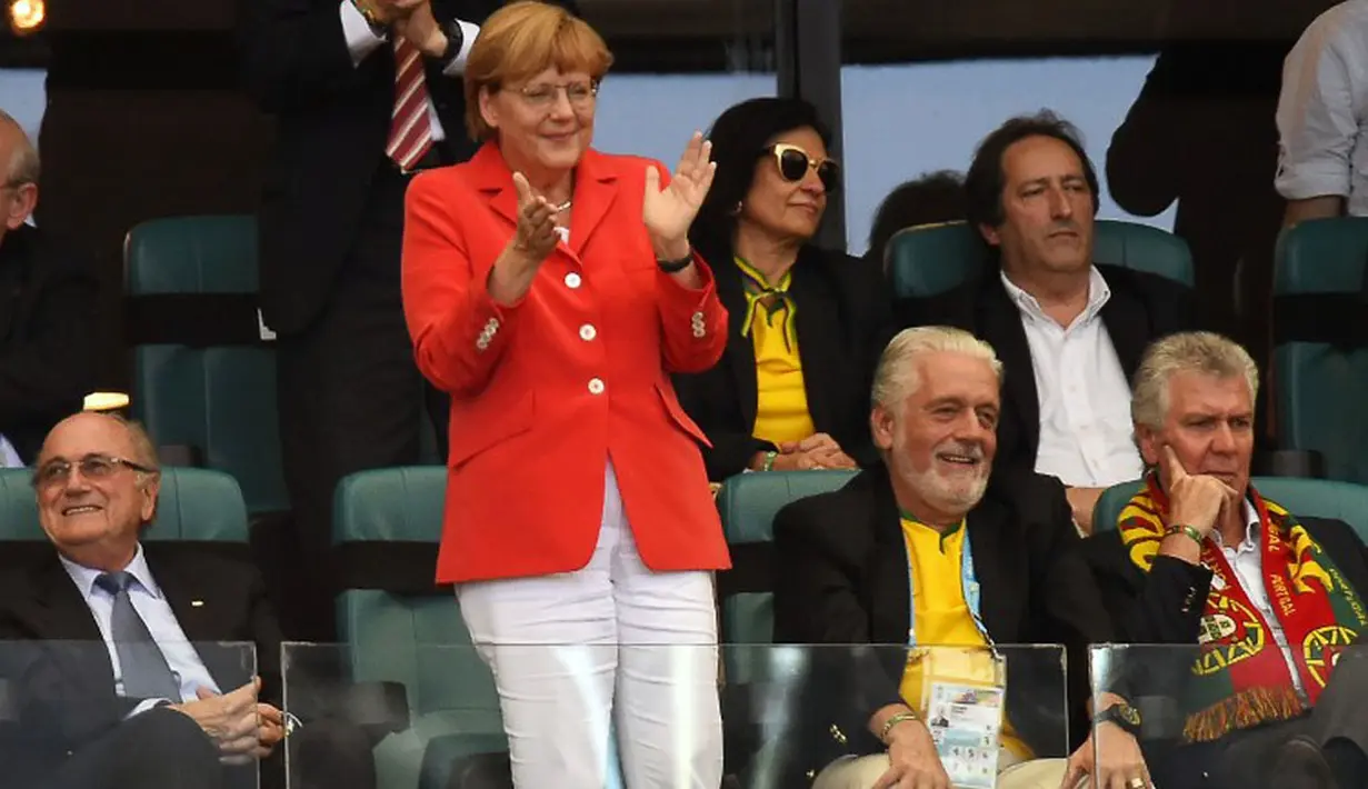 Kanselir Jerman, Angela Merkel berdiri memuji permainan tim asuhan Joachim Löw yang berlaga kontra Portugal di babak penyisihan Piala Dunia Grup G di Fonte Nova Arena, Brasil, (16/6/2014). (AFP PHOTO/Fabrice Coffrini)