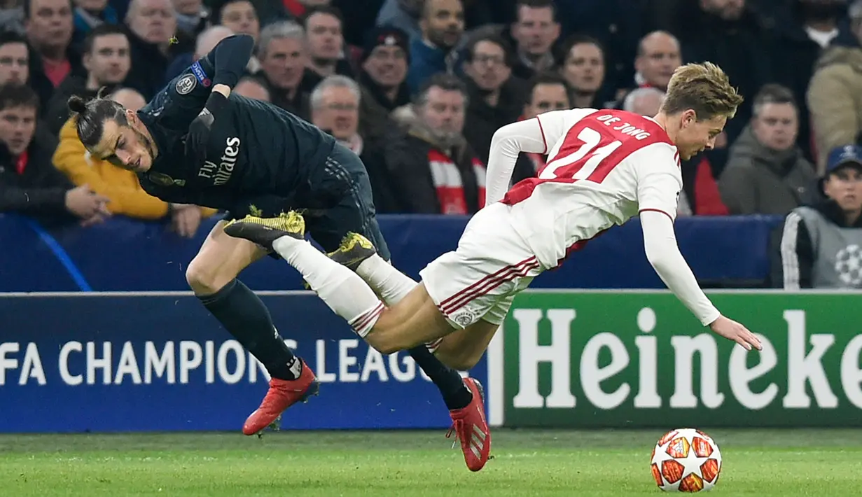 Penyerang Real Madrid, Gareth Bale berebut bola dengan gelandang Ajax Frenkie de Jong pada leg pertama 16 besar Liga Champions di Johan Cruijff ArenA, Rabu (13/2). Real Madrid harus bersusah payah menaklukkan Ajax dengan skor tipis 2-1. (JOHN THYS / AFP)