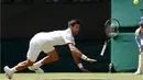Petenis Serbia, Novak Djokovic, melempar raketnya saat berusaha menjangkau bola pukulan petenis AS, Sam Querrey, dalam turnamen tenis Wimbledon di All England Lawn Tennis & Croquet Club, Wimbledon, Inggris, (2/7/2016). (Reuters/Paul Childs)