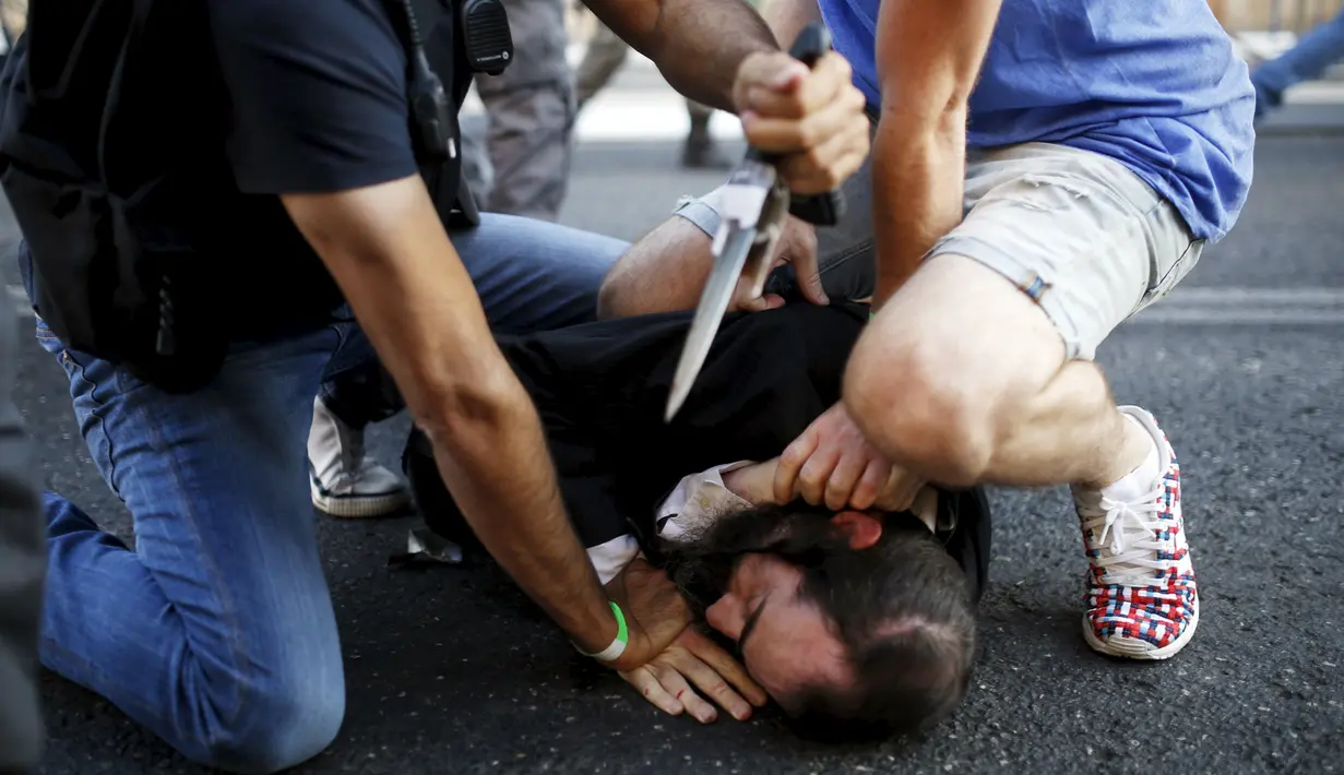 Sejumlah orang berusaha mengamankan pelaku penusukan di parade Gay Pride yang digelar di Yerusalem, Kamis (30/7/2015). Akibat penusukan tersebut, enam dari dua korban mengalami luka serius. (REUTERS/Amir Cohen) 