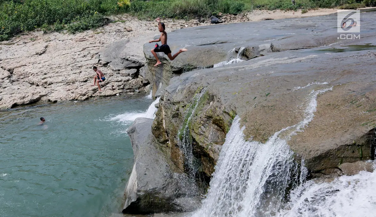 Seorang anak melompat saat berenang di aliran sungai Gunung Sari, Desa Tajur, Pasirmukti, Citeureup, Bogor, Jawa Barat (24/6/2019). Aliran sungai yang bening dan bersih dimusim kemarau dimanfaatkan oleh sejumlah warga sekitar utk main dan mandi disungai. (Kapanlagi.com/Budy Santoso)