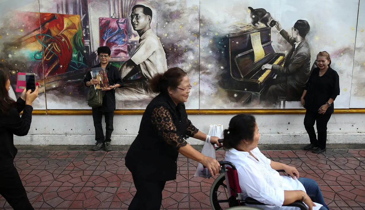 Warga berfoto di depan gambar raja Thailand Bhumibol Adulyadej di dekat Grand Palace, Bangkok, Thailand, Selasa (18/10). Setelah wafatnya raja Thailand, banyak respon positif untuk mengenang mendiang. (Reuters/Athit Perawongmetha)