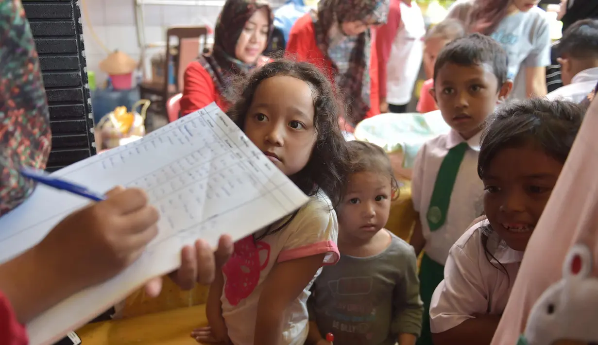 Petugas mendata nama anak-anak yang ingin disuntik vaksin difteri di sebuah klinik desa di Jakarta (11/12). Wabah Difteri ini telah menewaskan puluhan orang. (AFP Photo/Adek Berry)