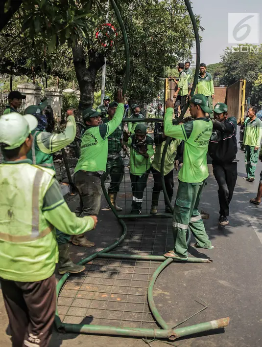 Petugas Suku Dinas Kehutanan Jakarta Pusat mengangkut pagar yang dirusak pengunjuk rasa usai demonstrasi di depan TPU Karet, Jakarta, Selasa (1/10/2019). Pengerusakan dilakukan pengunjuk rasa saat terlibat bentrok dengan polisi di kawasan tersebut. (Liputan6.com/Faizal Fanani)