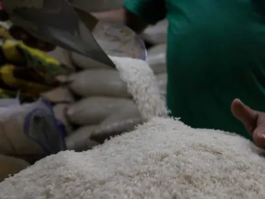 Pedagang memeriksa kondisi beras di pasar Cibubur, Jakarta, Senin (19/2/2024). (Liputan6.com/Herman Zakharia)