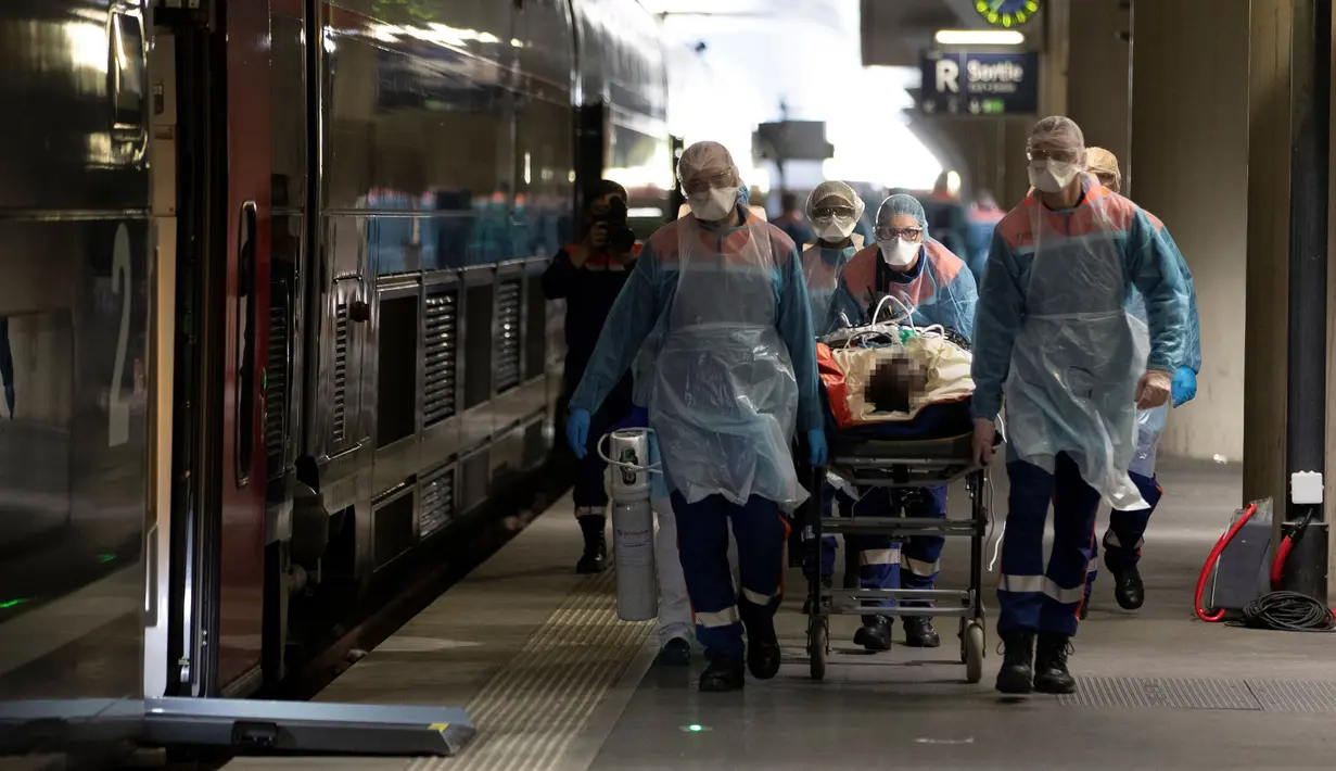 Petugas medis membawa pasien virus corona COVID-19 di Stasiun Gare d'Austerlitz di Paris, Prancis, Rabu (1/4/2020). Pasien COVID-19 dievakuasi menggunakan kereta kecepatan tinggi dari rumah sakit di Paris ke rumah sakit di Brittany dimana kasus tersebut masih terbatas. (Thomas SAMSON/AFP/POOL)