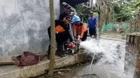 Petugas BPBD Cilacap dan relawan menguras sumur warga, sekaligus membersihkan lingkungan sekitar rumah. (Foto: Liputan6.com/Muhamad Ridlo)